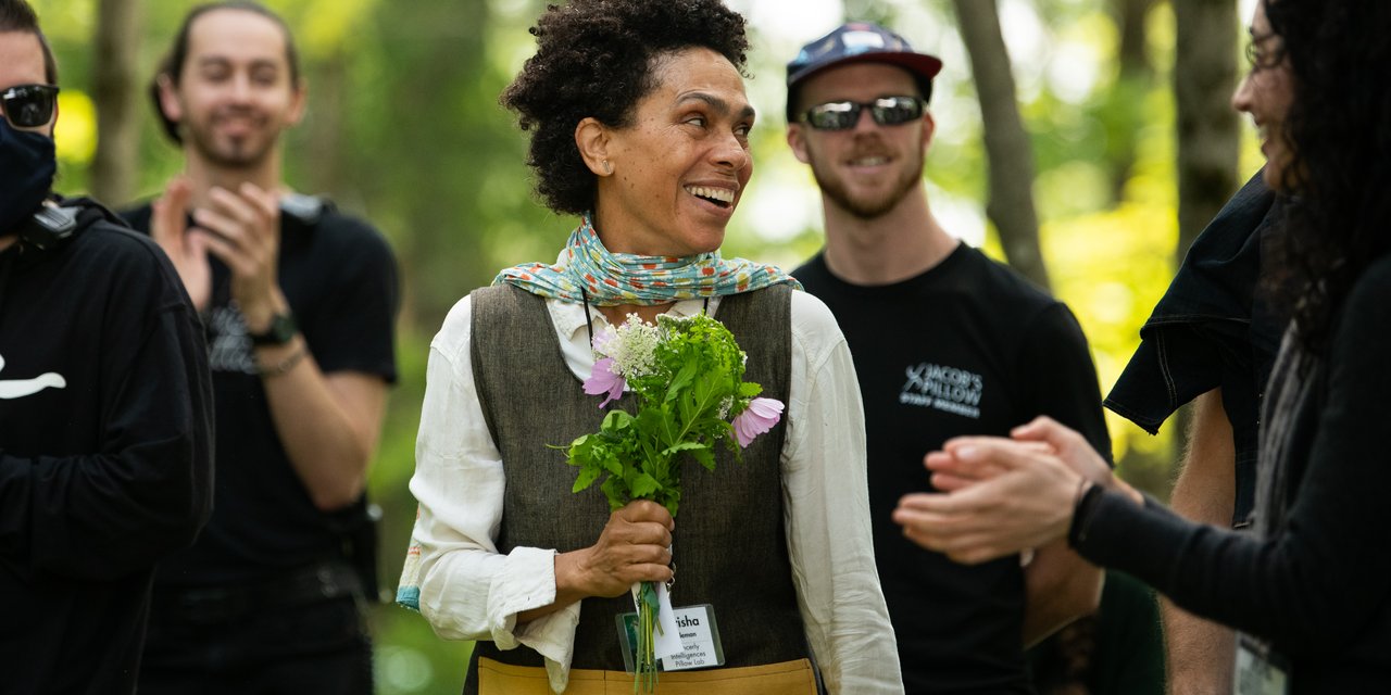Dancerly Intelligences resident artist smiling and holding gifted wildflowers, surrounded by staff.