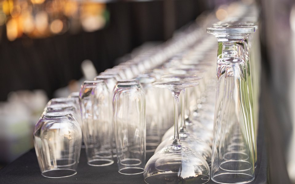 Five rows of glasses set on a black tablecloth stretch away from the viewer. The glasses are arranged by size, with the shortest row on the left and the tallest row on the right.