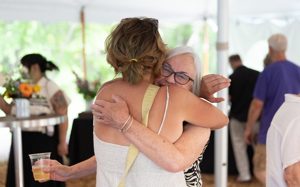 Two guests embracing at a function in an event tent.