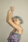 Naomi Funaki is a tap dancer with sky blue bob hair, wearing a denim dress designed by KENTO USTUBO. Naomi is putting her arms up and looking at the camera.