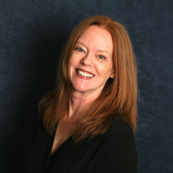 A woman with red hair and blue eyes poses for the camera. Sandy Russell, instructor for Family Music and Dance.
