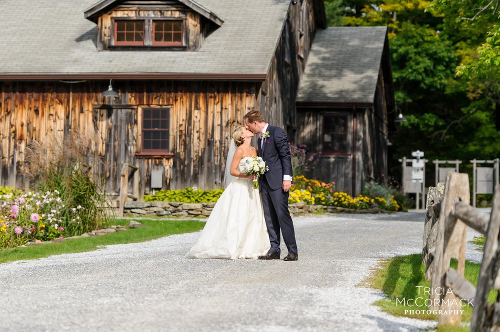 A bride and groom kiss on a gravel path on the Jacob's Pillow campus.